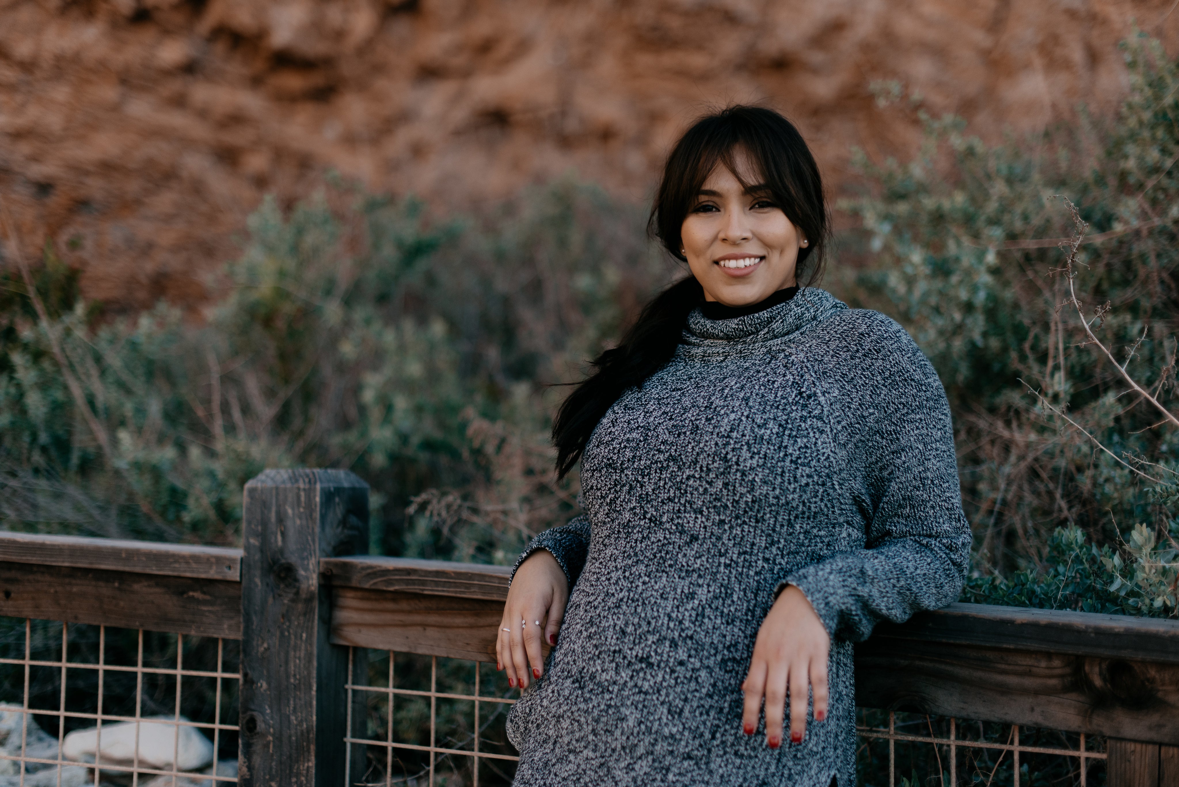 files/woman-in-a-sweater-smiles-as-she-leans-against-a-fence.jpg